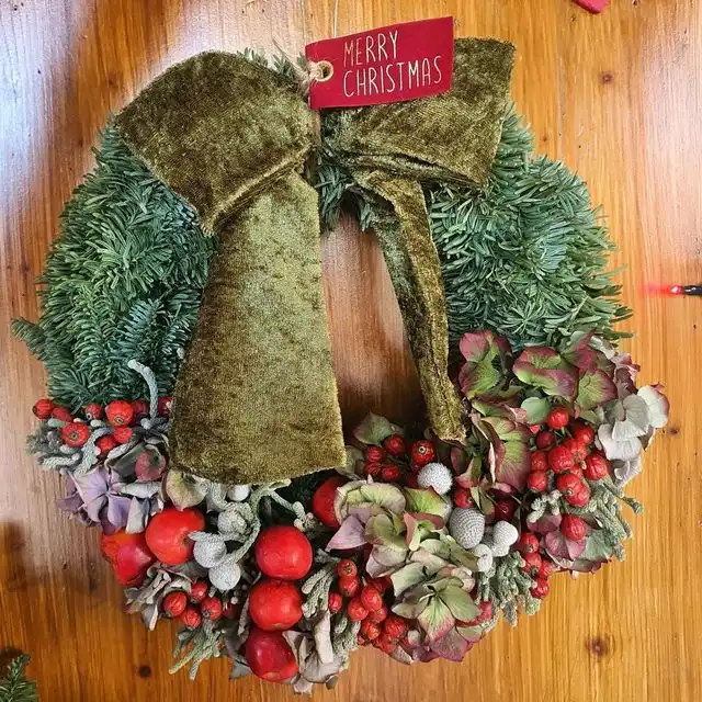 Ghirlanda di Natale con fiocco di velluto verde e bacche rosse