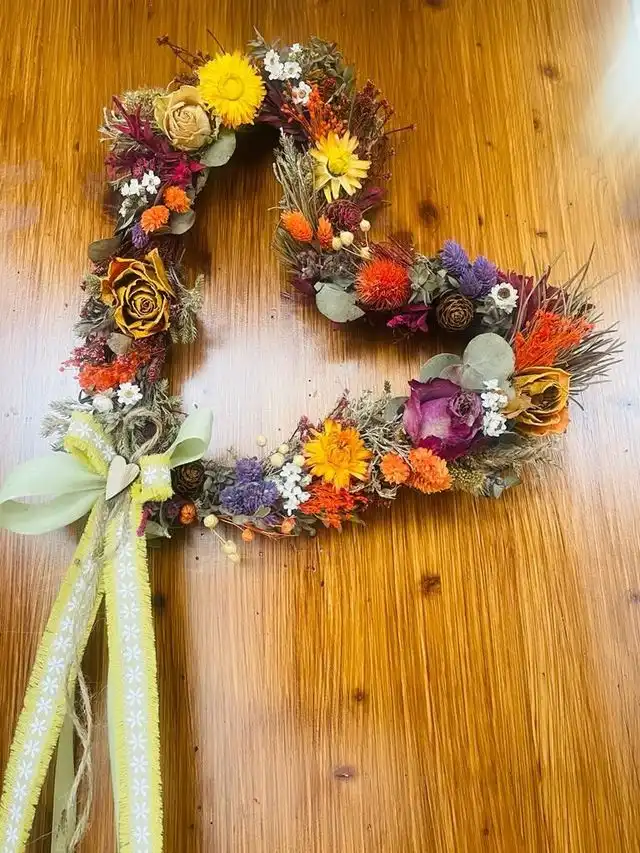 Cuore di fiori secchi colorati su un tavolo di legno